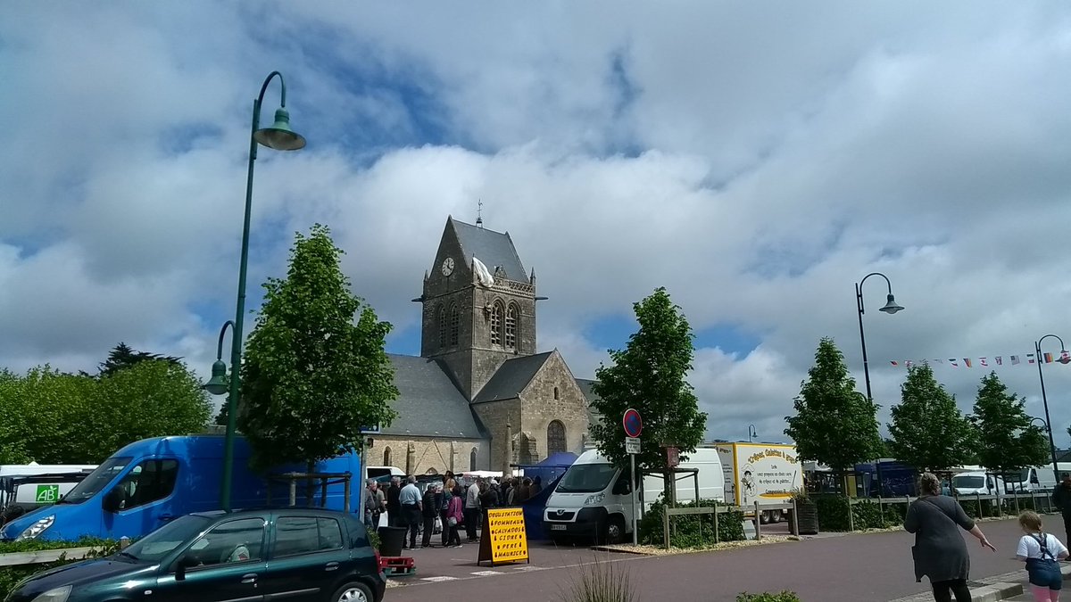 Market day in Ste Mere Eglise, with dummy US paratrooper hanging from the church tower (photo: James Kemp)